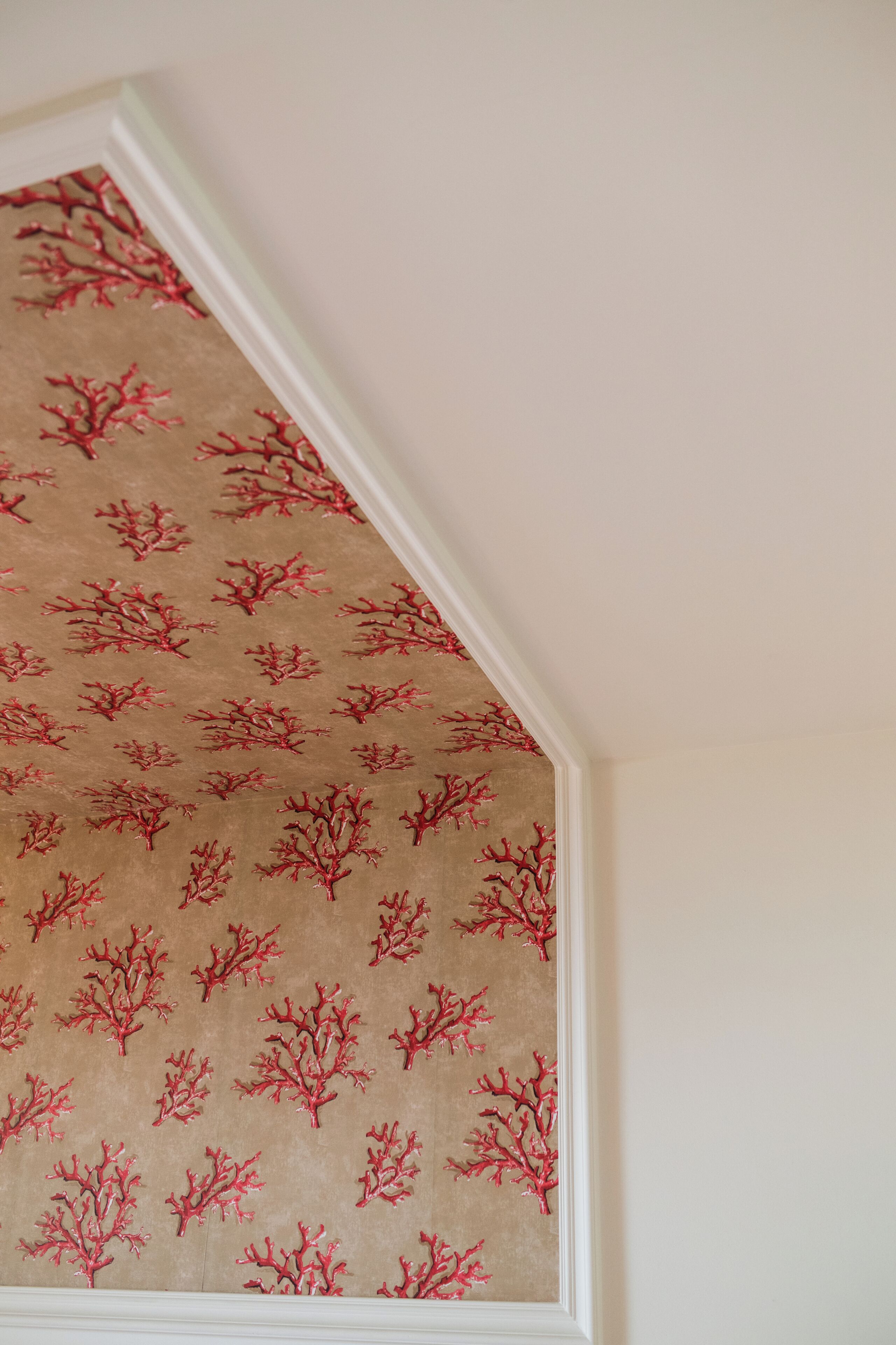Un muro rivestito con carta da parati decorata con motivi che ricordano alberi, in tonalità di rosso.