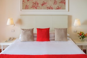 A hotel room with a bed, two bedside lamps, a phone, and a painting on the wall. - Hotel Caparena (Taormina)