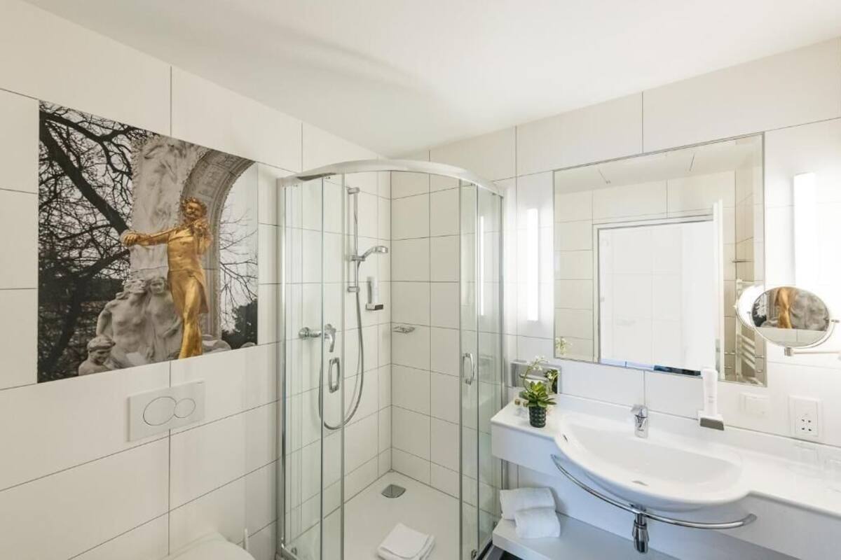 A modern bathroom with a glass shower enclosure, a white sink, and a large mirror.