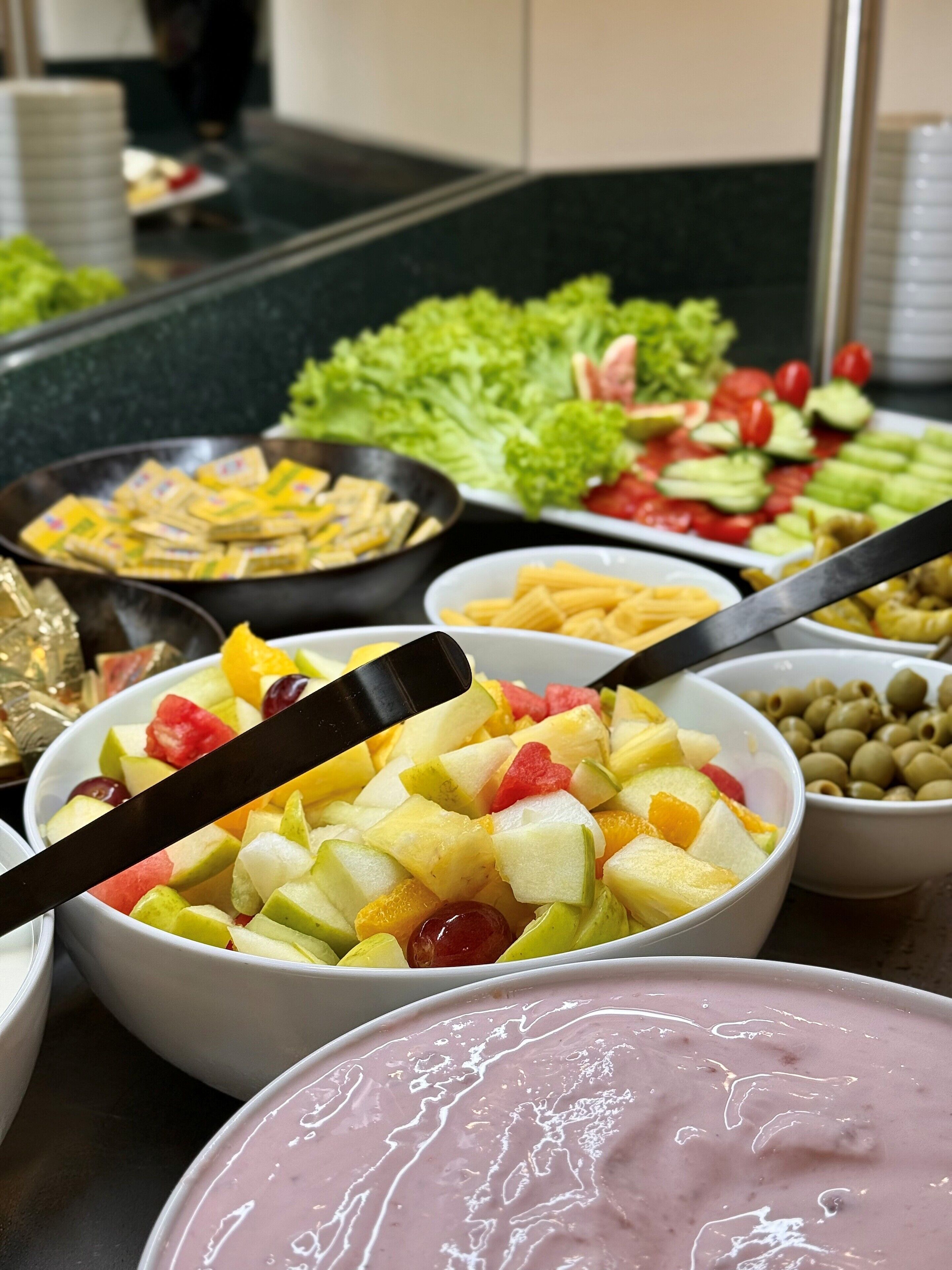 Een buffet met diverse soorten eten, zoals fruit, groenten en pasta.