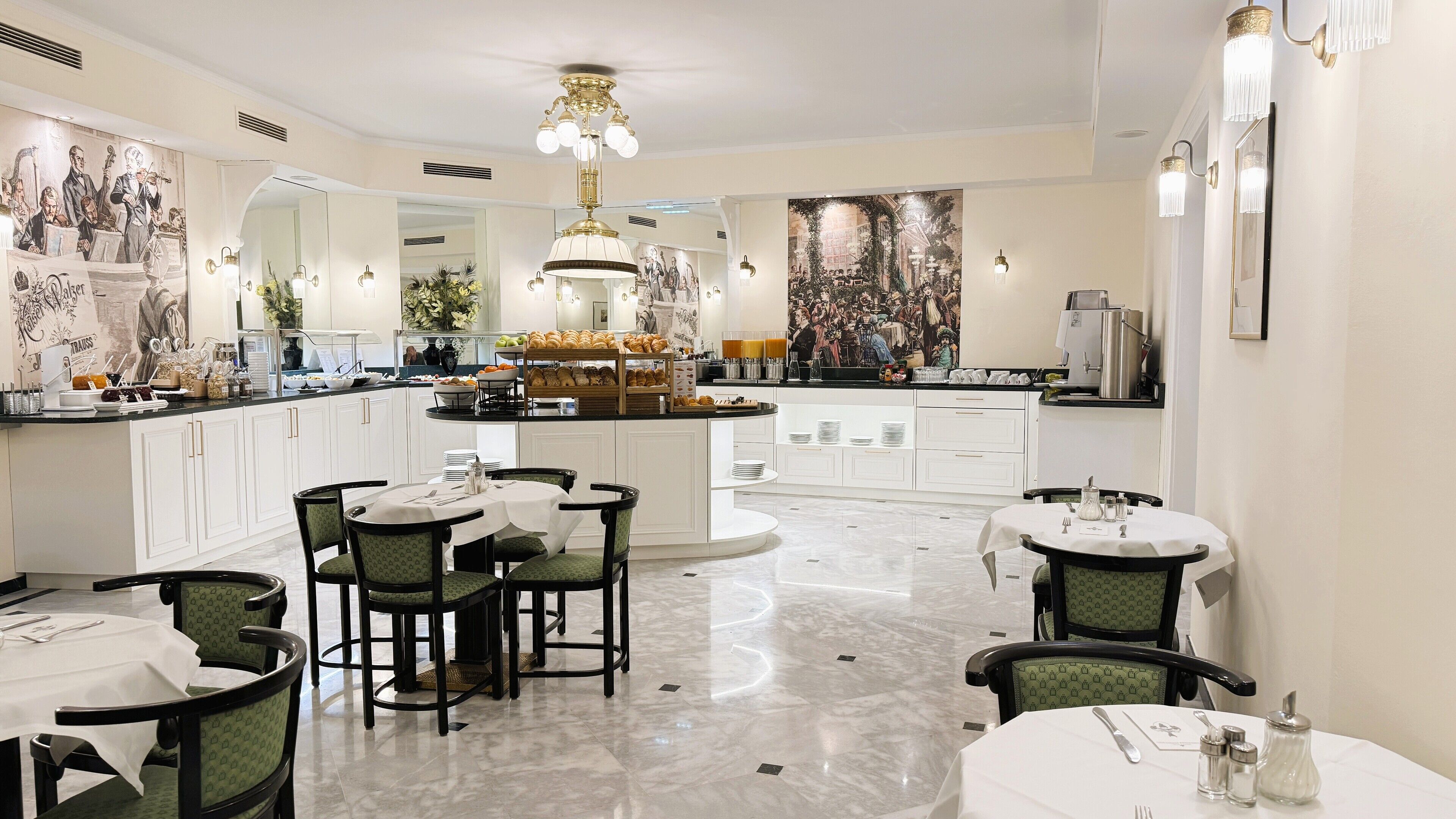 A modern dining area with white cabinetry, marble flooring, and green upholstered chairs.