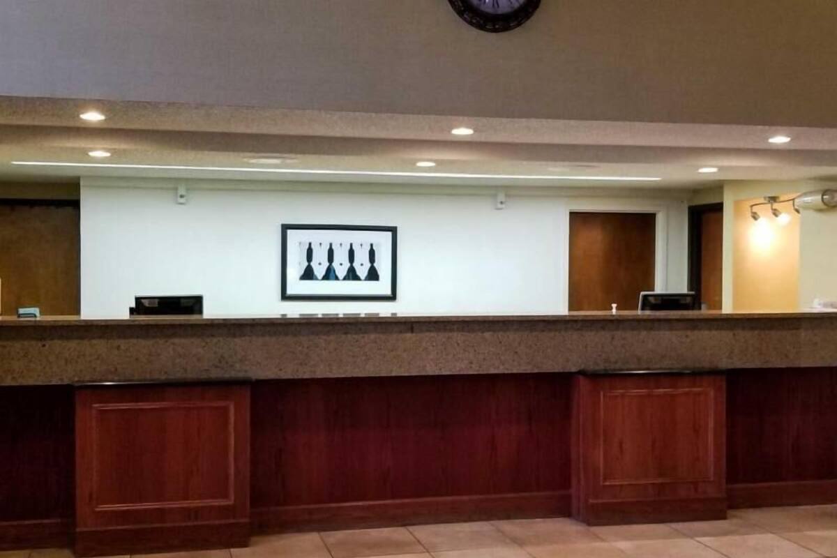 A reception desk with a framed artwork above it, a clock on the wall, and a counter with a wooden panel design.