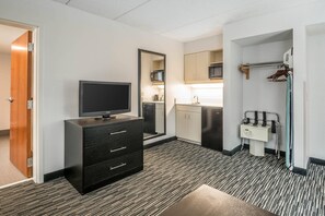 A compact hotel room with a flat-screen TV, a black dresser, a microwave, a sink, and a small exercise area with a towel rack. - Comfort Inn University (Gainesville)