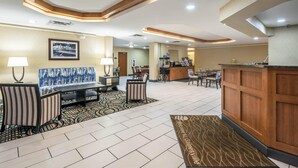 A hotel lobby with a reception desk, seating area, and a view of the dining area. - Comfort Inn Gainesville - University Area (Gainesville)