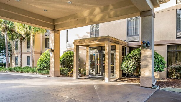 A modern building entrance with a covered entrance area, glass doors, and surrounding greenery. - Comfort Inn Gainesville - University Area (Gainesville)