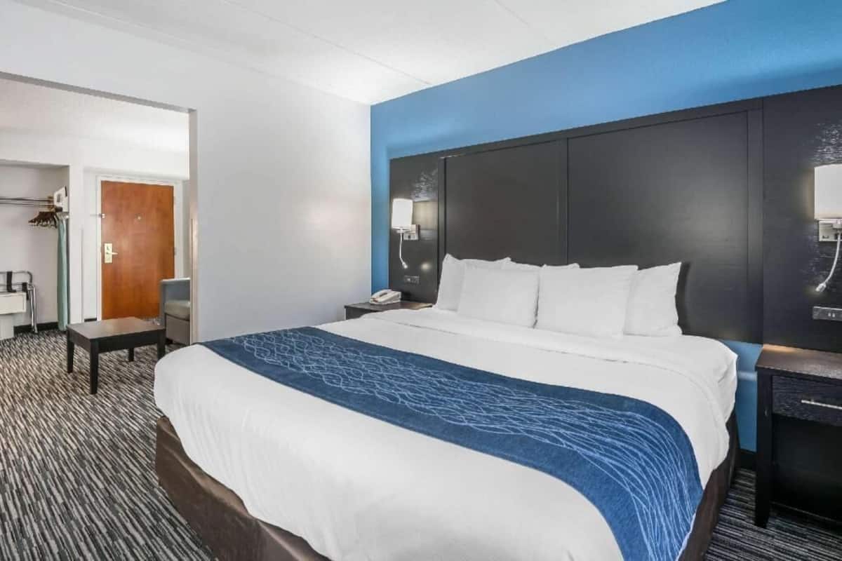 A hotel room with a large bed, a bedside table, a nightstand, a desk, and a wardrobe.