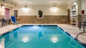 An indoor swimming pool with clear water, tiled walls, and a blue chair near the pool. - Comfort Inn Crystal Lake - Algonquin (Crystal Lake)