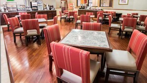 A hotel dining area with multiple tables and chairs, a coffee station, and a counter with a menu. - Comfort Inn Crystal Lake - Algonquin (Crystal Lake)