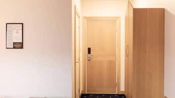 Un pasillo con puerta de madera, un certificado enmarcado en la pared y suelo alfombrado.