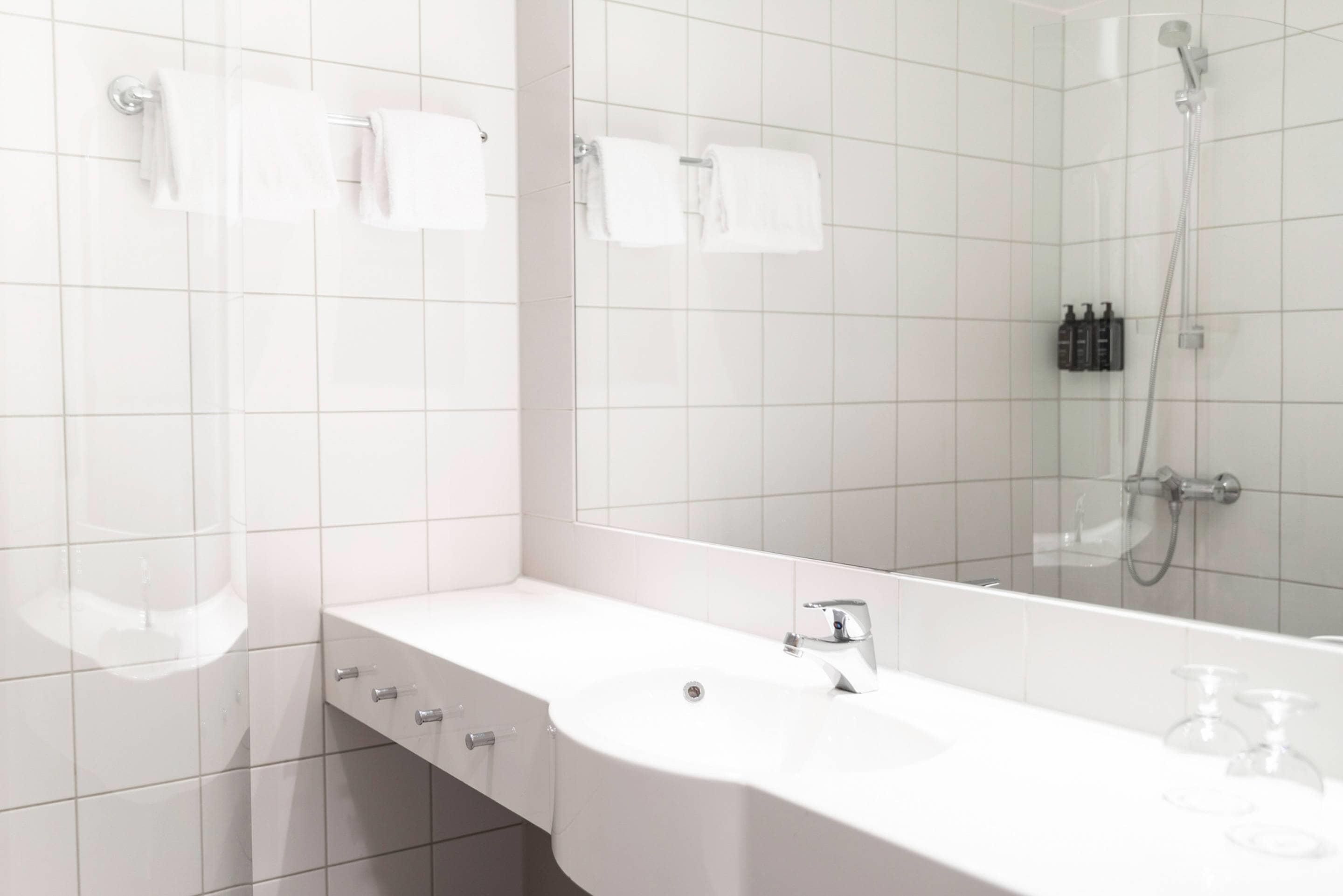 A bathroom with a white sink, mirror, and shower.