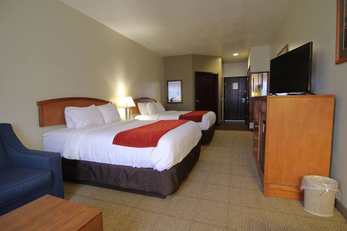 Une chambre d’hôtel avec deux lits, une télévision, un bureau et une chaise.