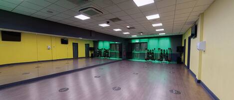 A large, empty gym with a wooden floor and green lighting.
