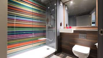 A modern bathroom with a glass shower enclosure, a white toilet, and a wooden vanity.