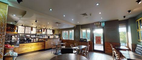 A restaurant with a wooden interior, a central round table, and a counter with food items.