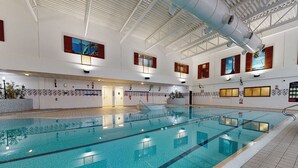 En indendørs swimmingpool med tydelige baner, flisegulv og et højt loft med synlige konstruktionselementer.