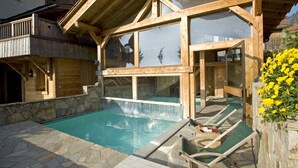 A wooden villa with a swimming pool, outdoor seating, and a stone wall. - Hotel Chalet Les Saytels, BW Signature Collection (Le Grand-Bornand)