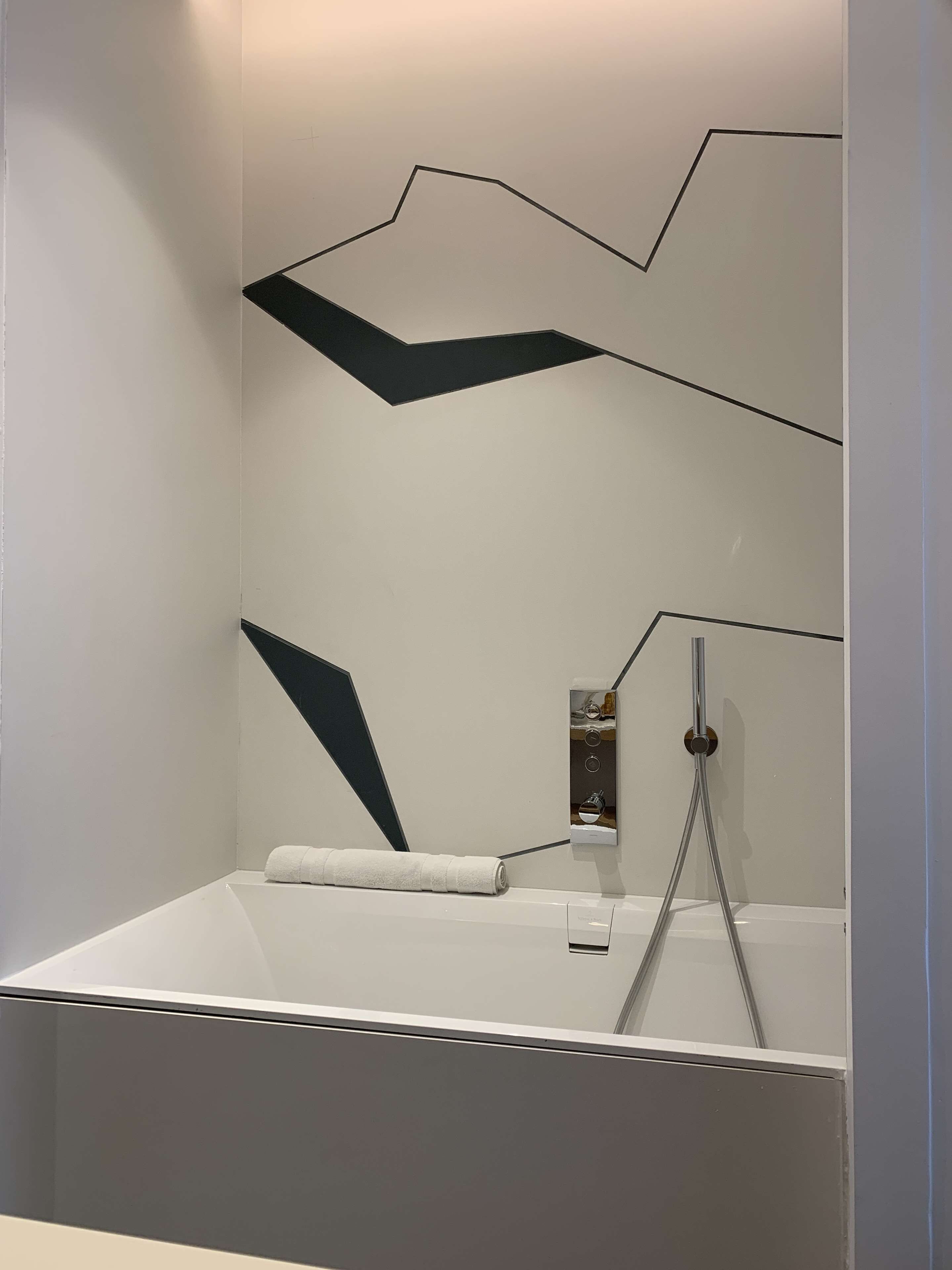 Un baño moderno con una bañera independiente, una toalla y un espejo instalado en la pared.