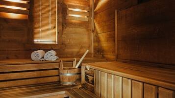 Una sauna de madera con bancos, una ventana con persianas y un cubo de madera con un cepillo.