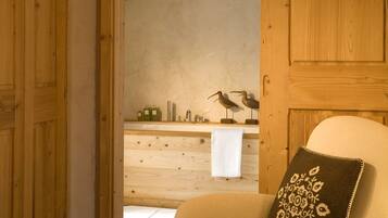 Relax in a warm and inviting space with a comfortable armchair and a cozy bathroom featuring a sink and towel rack.