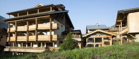 Un edificio de madera de varios pisos con balcones, rodeado de vegetación y montañas.