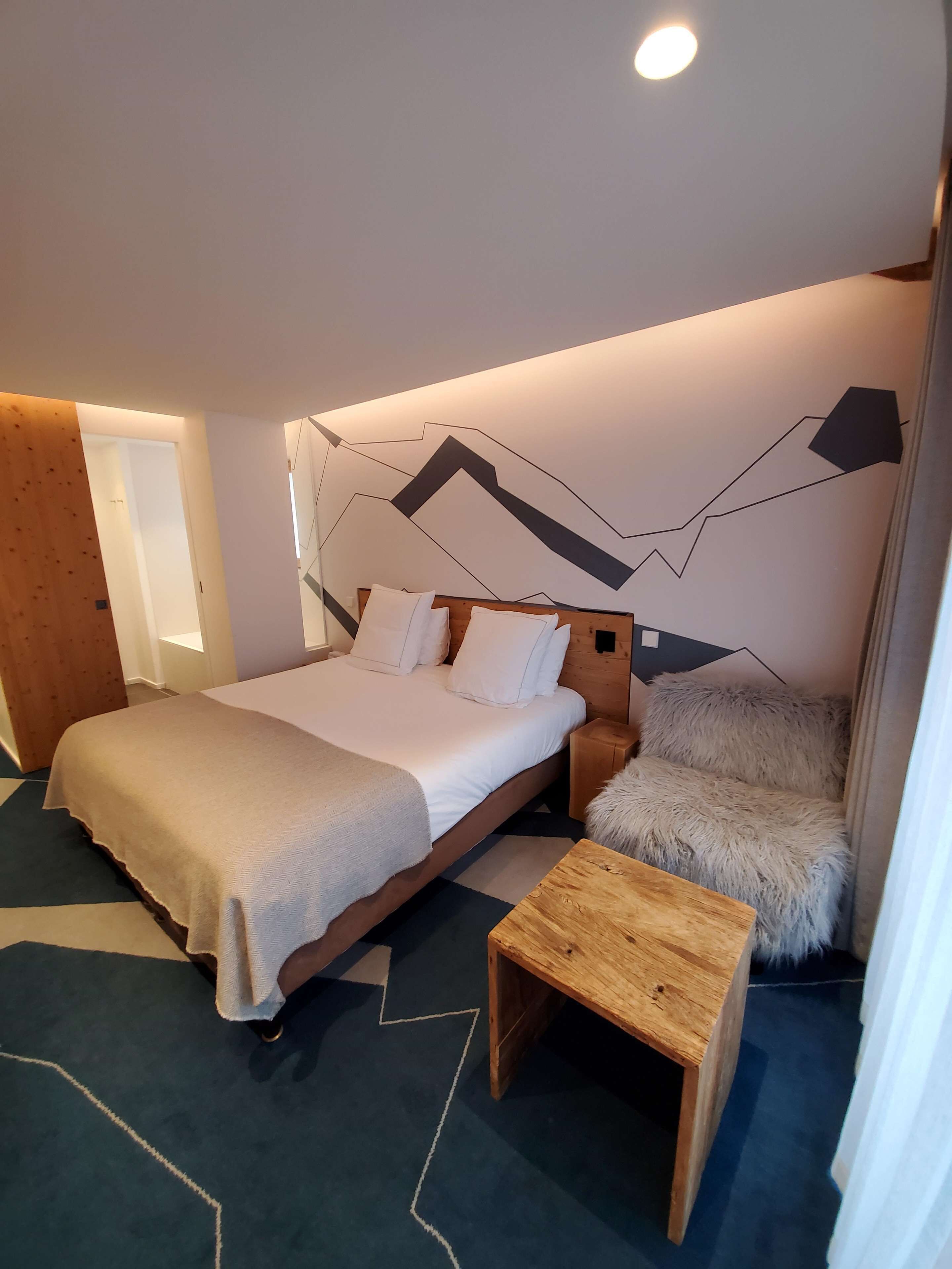 Une chambre à coucher moderne avec un grand lit, une table de chevet en bois, un oreiller moelleux et une petite table en bois.