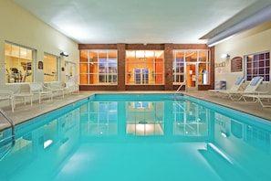 An indoor swimming pool with clear blue water, surrounded by lounge chairs and a brick wall. - Holiday Inn Express & Suites Manchester by IHG (Manchester)
