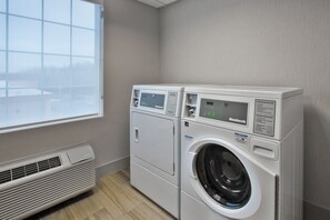 A laundry room with two front-loading washing machines, a vent, and a window. - Holiday Inn Express & Suites Manchester by IHG (Manchester)