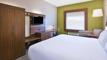 A hotel room with a large bed, a desk with a flat-screen TV, a wardrobe, and a window with a view.
