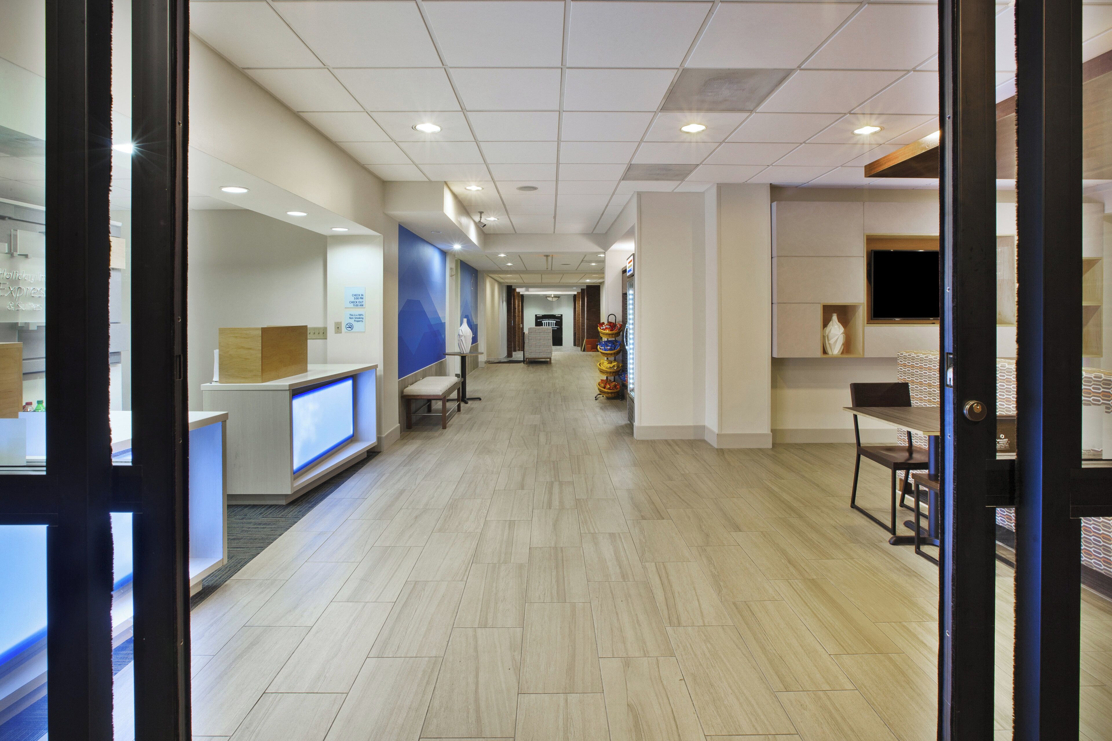 A hotel reception area with a reception desk, seating area, and a TV mounted on the wall.