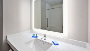 A modern bathroom with a white sink, a large mirror, and a shower visible in the reflection. - Holiday Inn Express & Suites Manchester by IHG (Manchester)