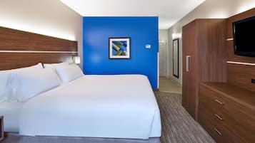 Quarto de hotel com uma cama grande, televisão, guarda-roupa e uma parede azul de destaque.