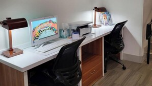 A modern office space with a white desk, two black office chairs, a computer monitor, a keyboard, a lamp, and a framed artwork on the wall. - Holiday Inn Express & Suites Manchester by IHG (Manchester)