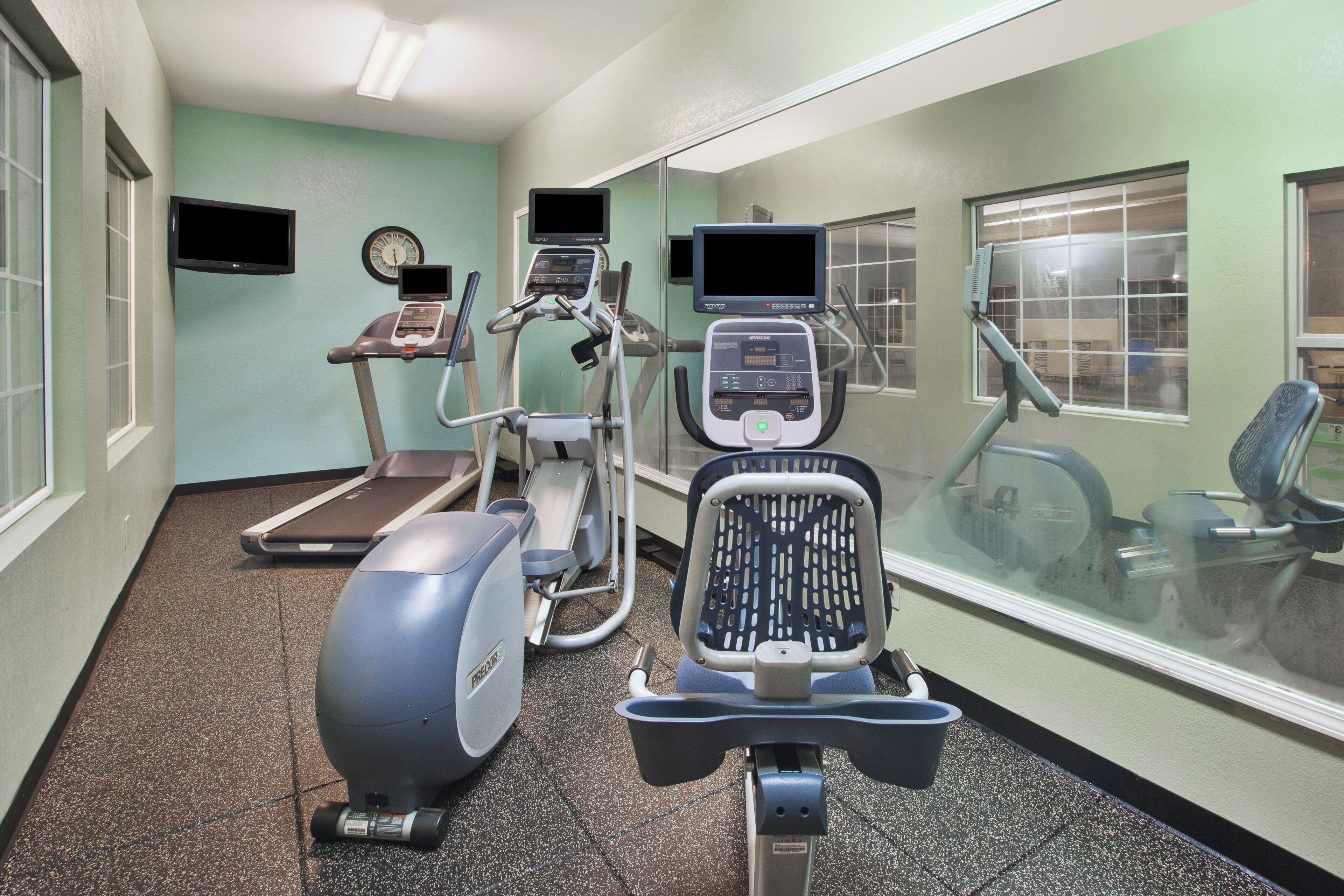 Un centre de remise en forme équipé de tapis de course, d’un vélo elliptique et d’un vélo d’appartement.
