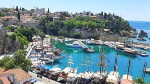 A coastal town with a marina, historic buildings, and a prominent castle wall. - Puding Hotel (Antalya)
