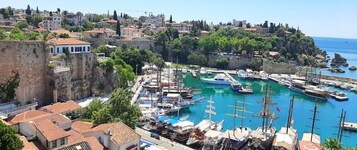 A coastal town with a marina, historic buildings, and a prominent castle wall.