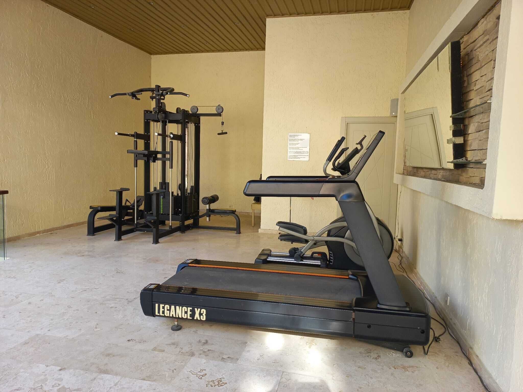 A gym with a Legance X3 elliptical, a weight machine, and a bench.