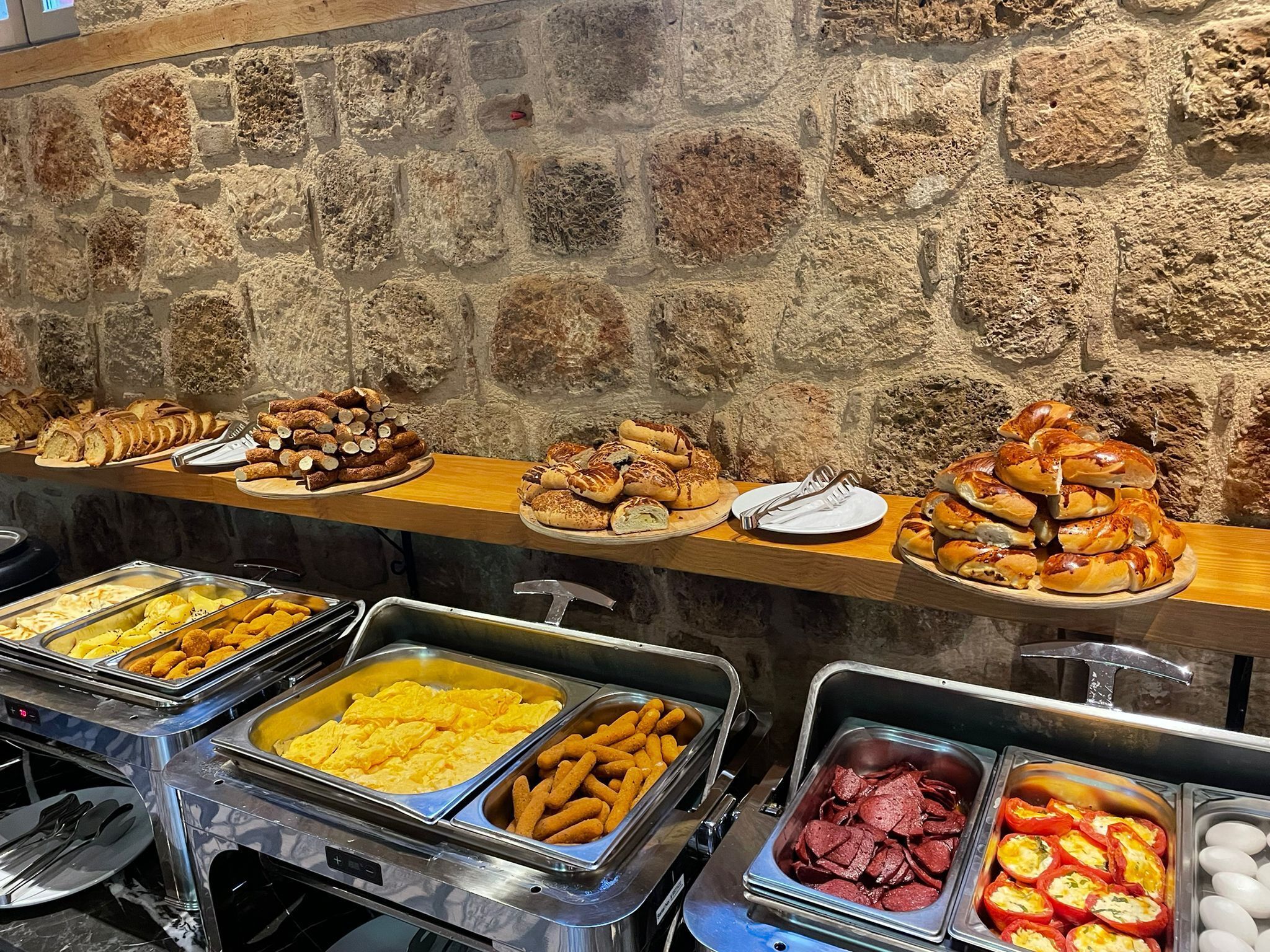 A buffet with various food items including bread, pastries, and a selection of meats and cheeses.