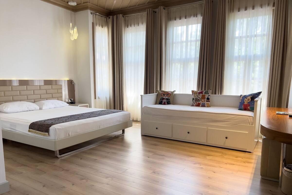 A modern bedroom with a bed, a sofa bed, and a small table.