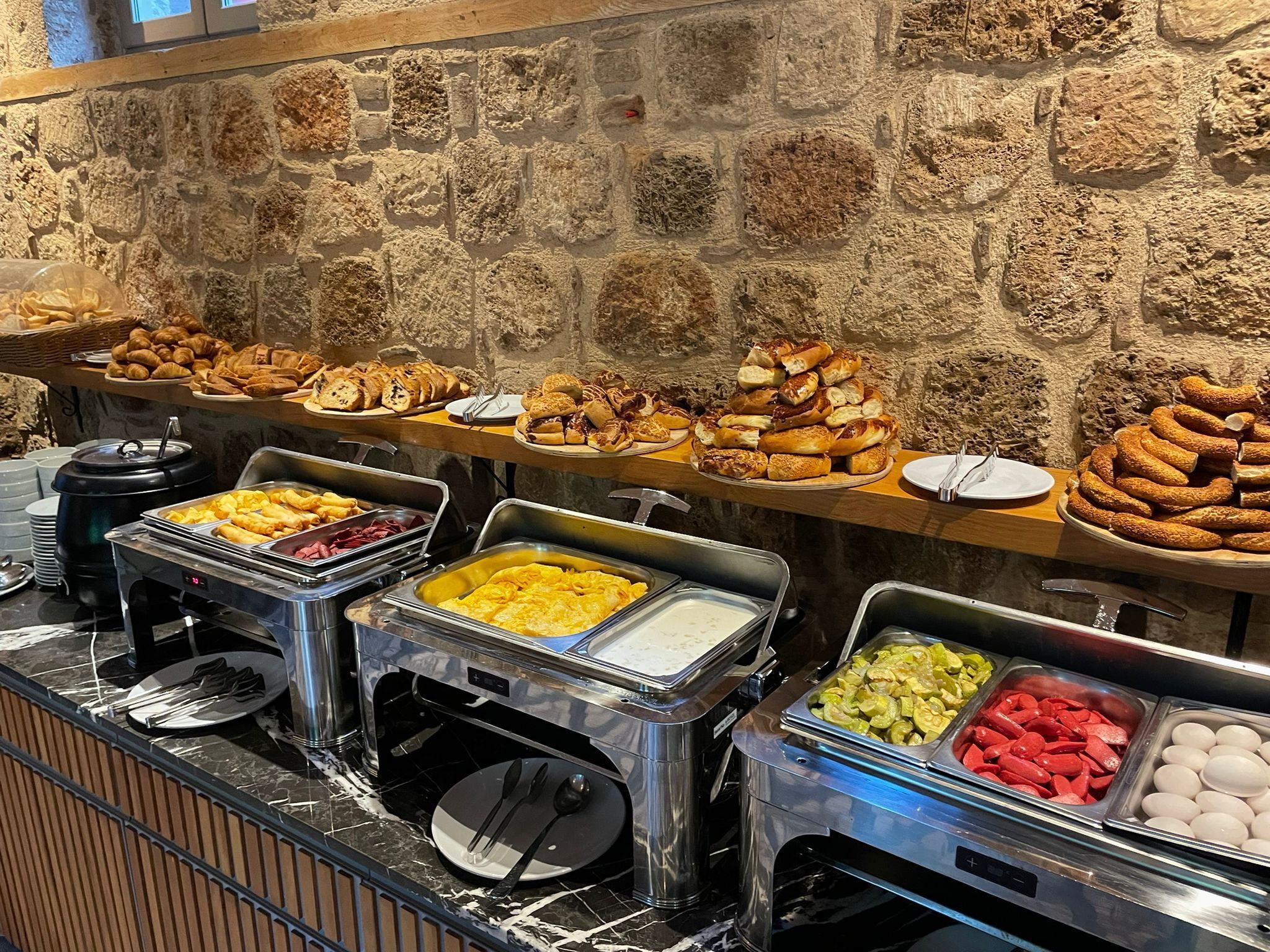 A buffet with various food options, including pastries, sandwiches, and different types of meats and cheeses.