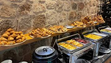 A buffet with various food items and a stone wall in the background.