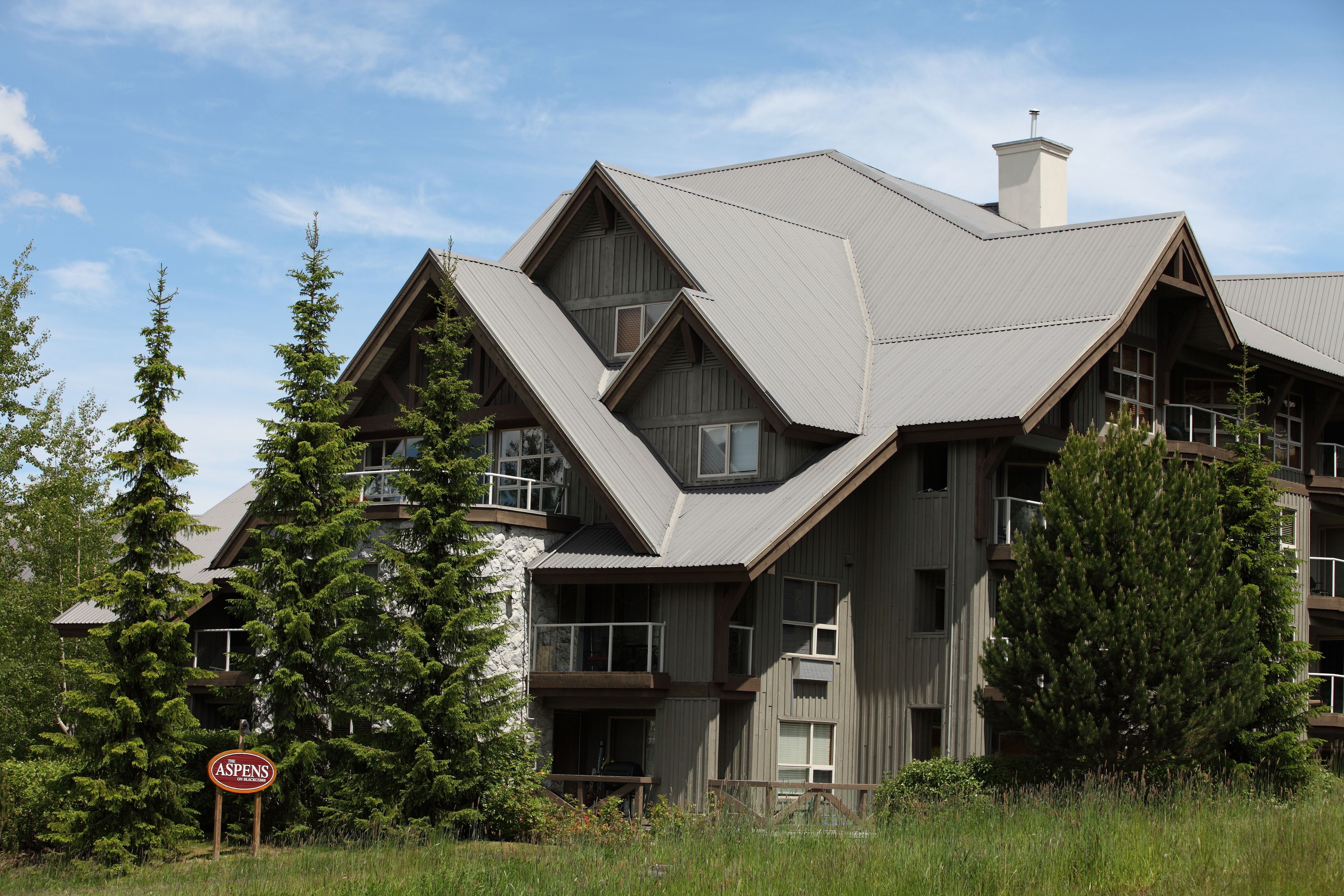 A multi-story building with a sloped roof, surrounded by trees.