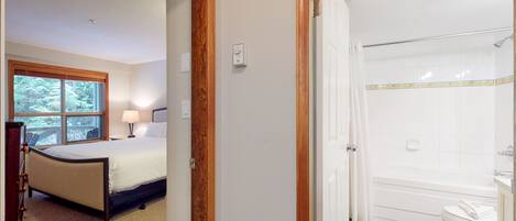 Een slaapkamer met een bed, een raam en een badkamer met een bad en toilet.