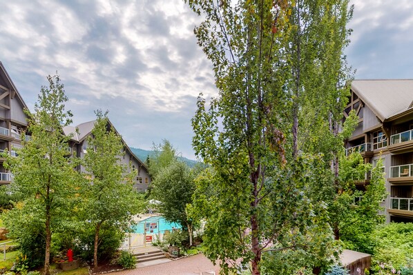 A courtyard with buildings, trees, and a blue structure. - Aspens on Blackcomb (Whistler)