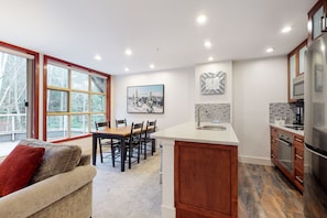 A modern kitchen with a large island, wooden cabinets, and a built-in oven. - Aspens on Blackcomb (Whistler)