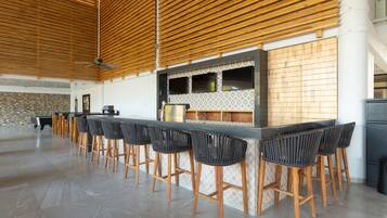 A modern kitchen with a bar area, wooden slatted ceiling, and a stone accent wall.