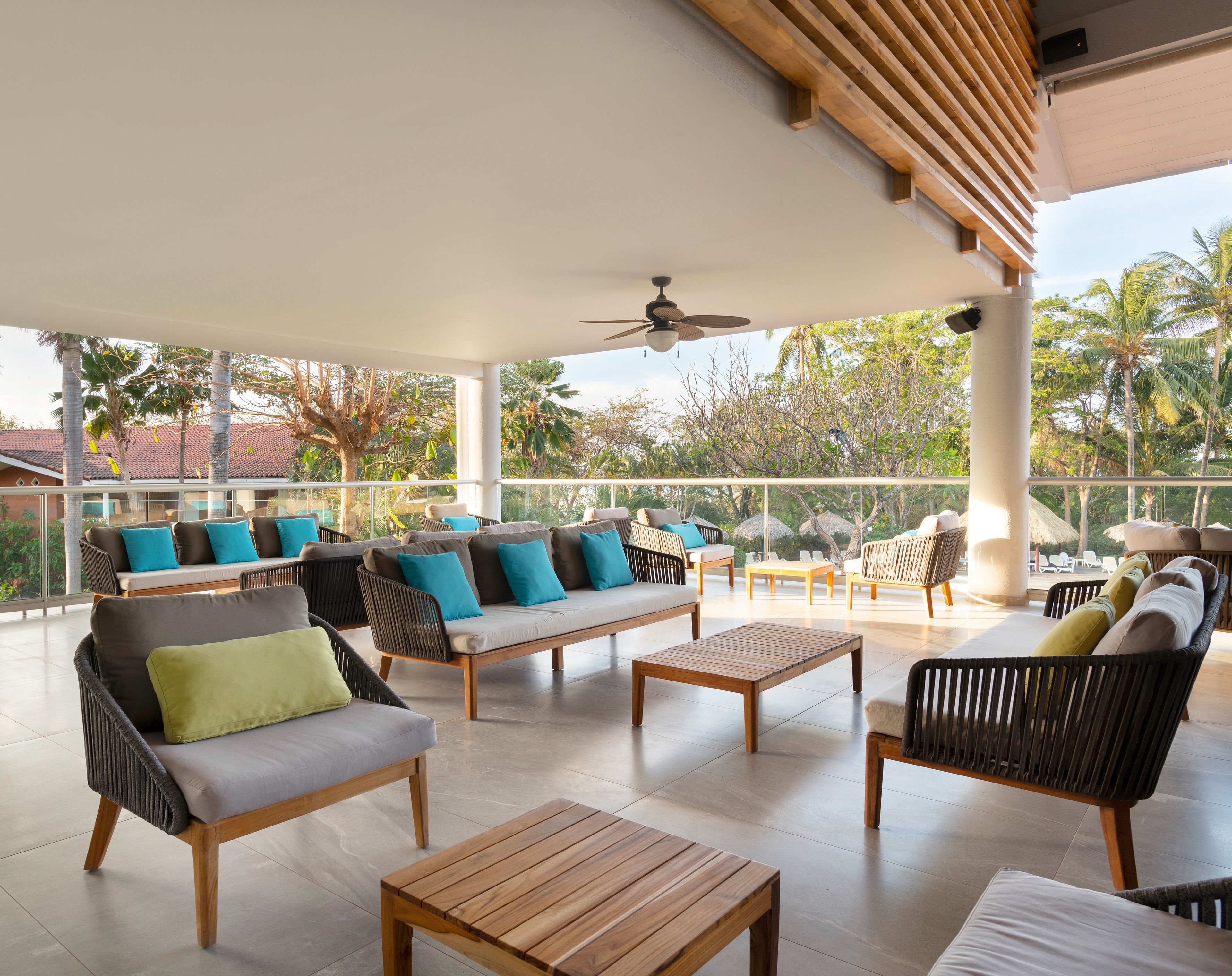 Amplia zona de estar al aire libre con diversas opciones de asientos, incluyendo sofás y sillones, dispuestas alrededor de mesas de madera.