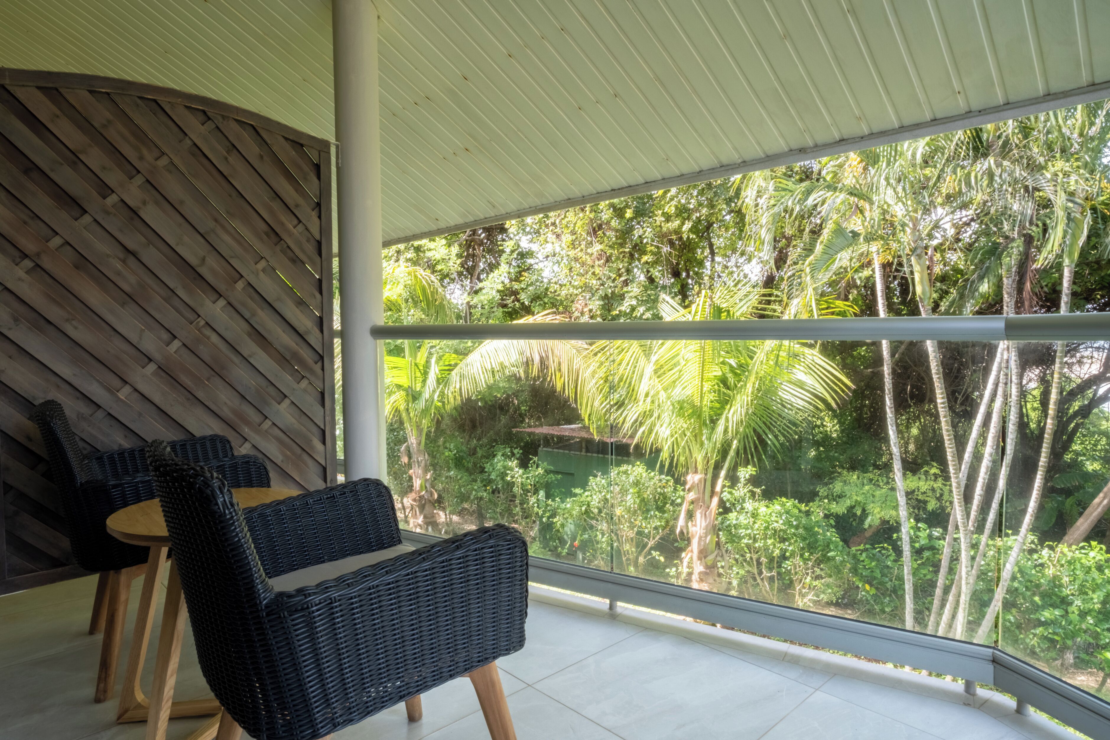 A balcony with wicker furniture and a view of tropical vegetation.