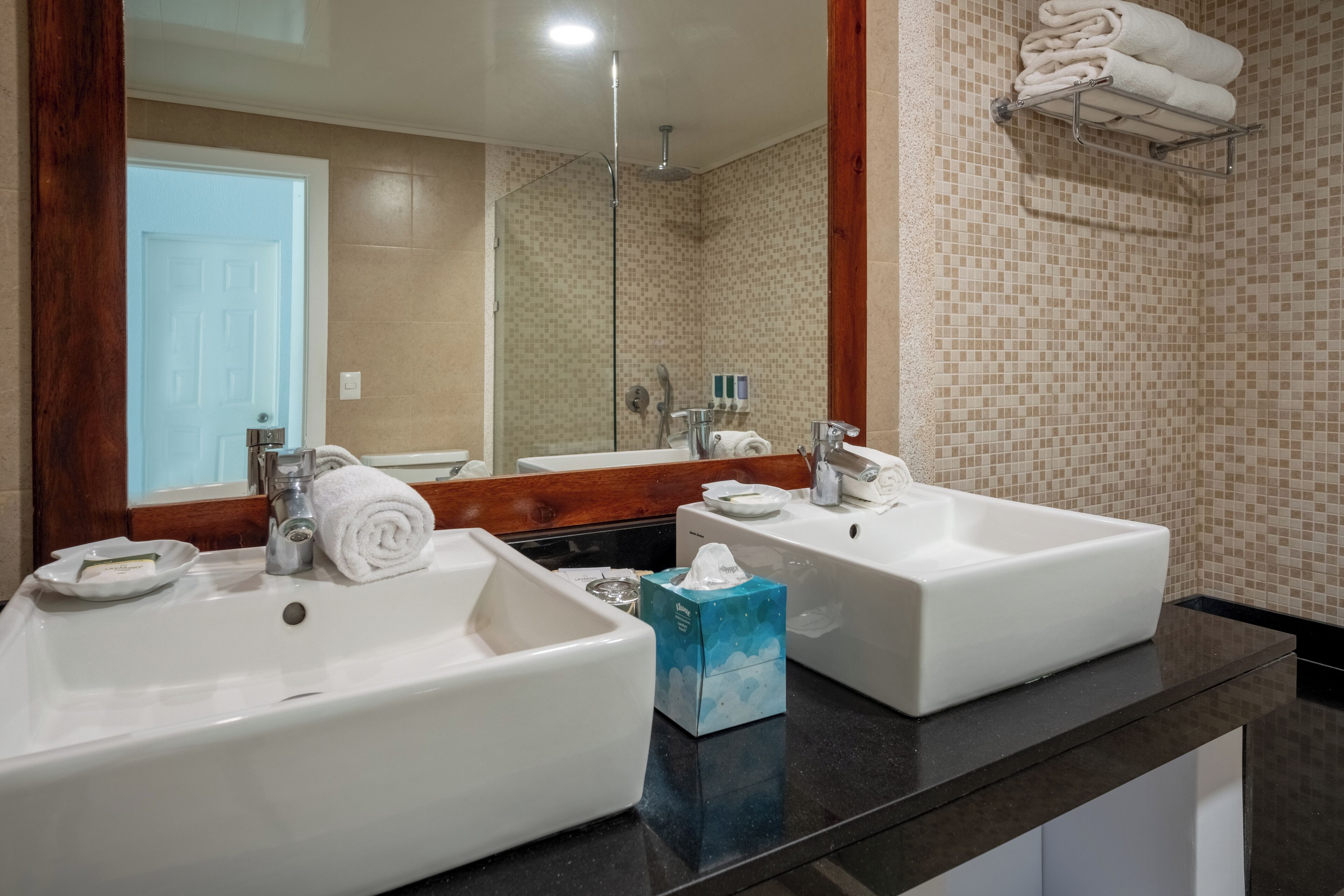Un baño con dos lavamanos, un espejo y un perchero para toallas.