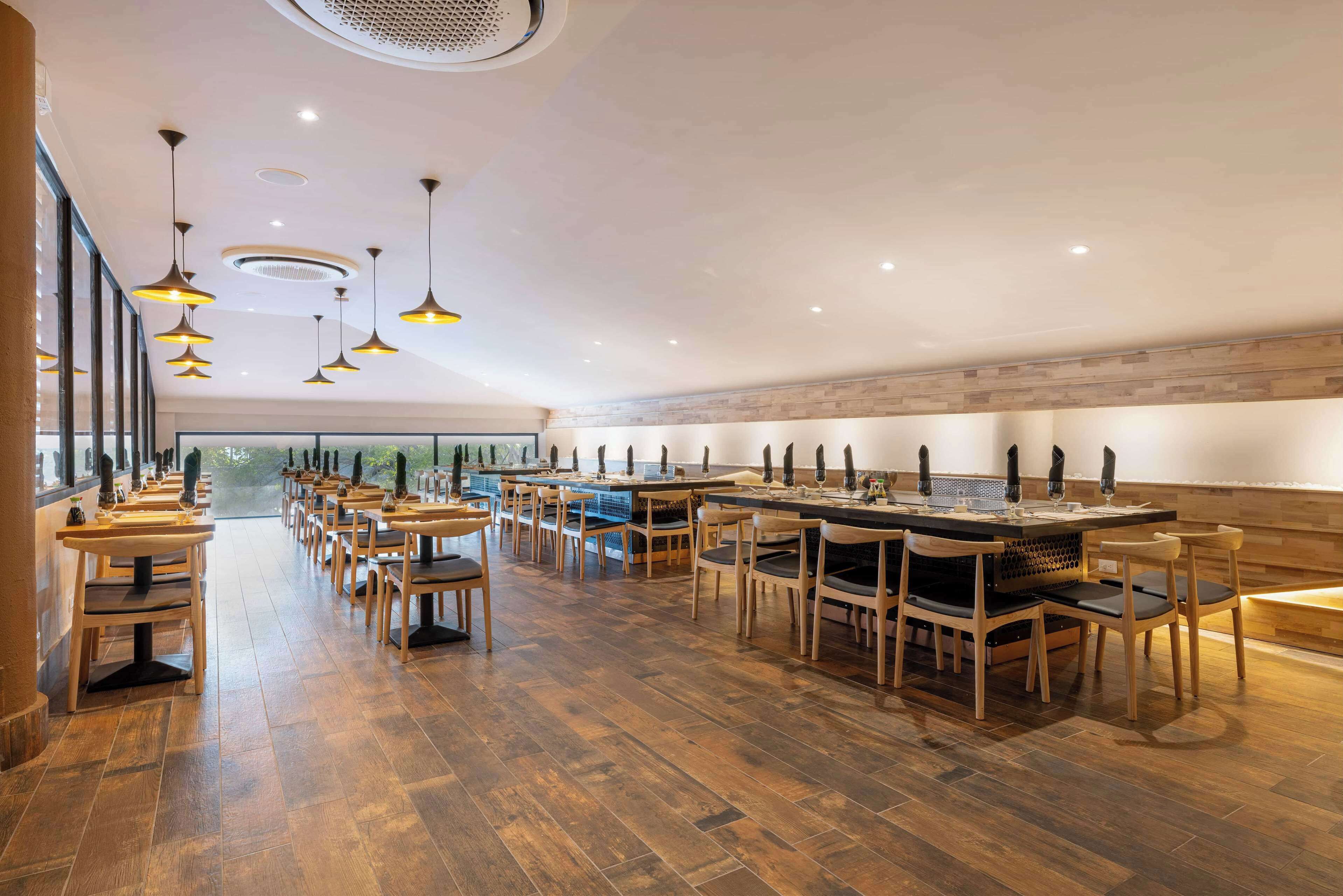 Ein geräumiges Restaurant mit Holzboden und mehreren Tischen und Stühlen.