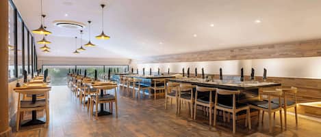 Un restaurante amplio con suelo de madera y varias mesas y sillas.